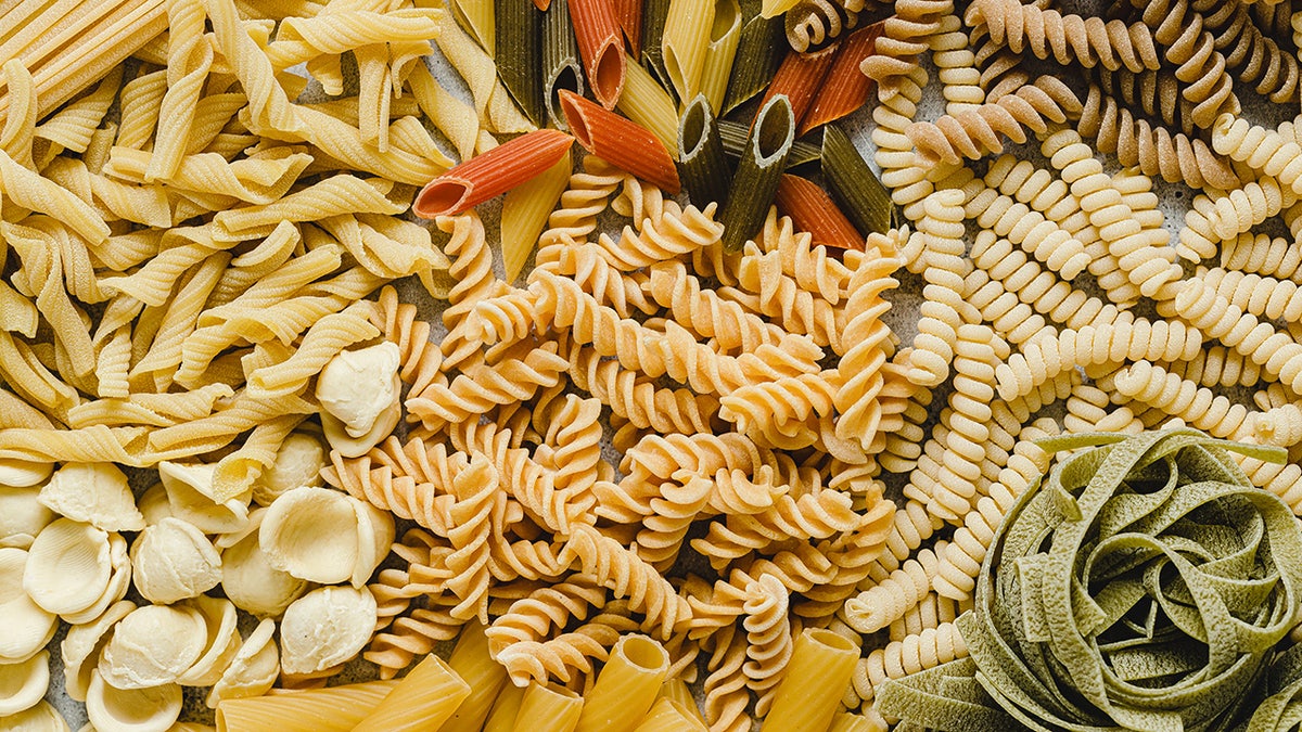 Table top view of variety of uncooked pasta. Full frame of different types of dried pasta on table.