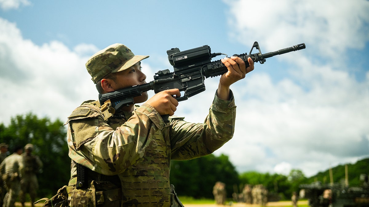 American soldier peers through Smartshooter Smash 2000L connected to the M4A1 rifle