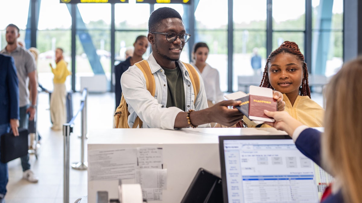 Travelers hand over passports at the airport desk