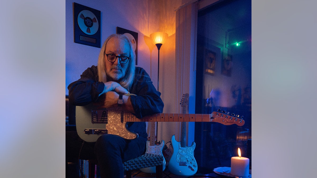 Alan Niven leaning against a guitar