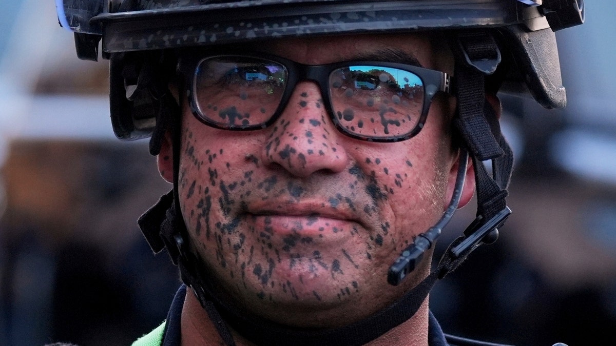 A police officer's face is covered in pepper spray outside the Metropolitan Detention Center of downtown Los Angeles, Sunday, June 8, 2025, following last night's immigration raid protest.