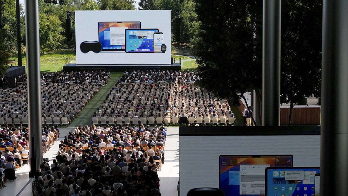 A crowd of people listening to an Apple presentation outside