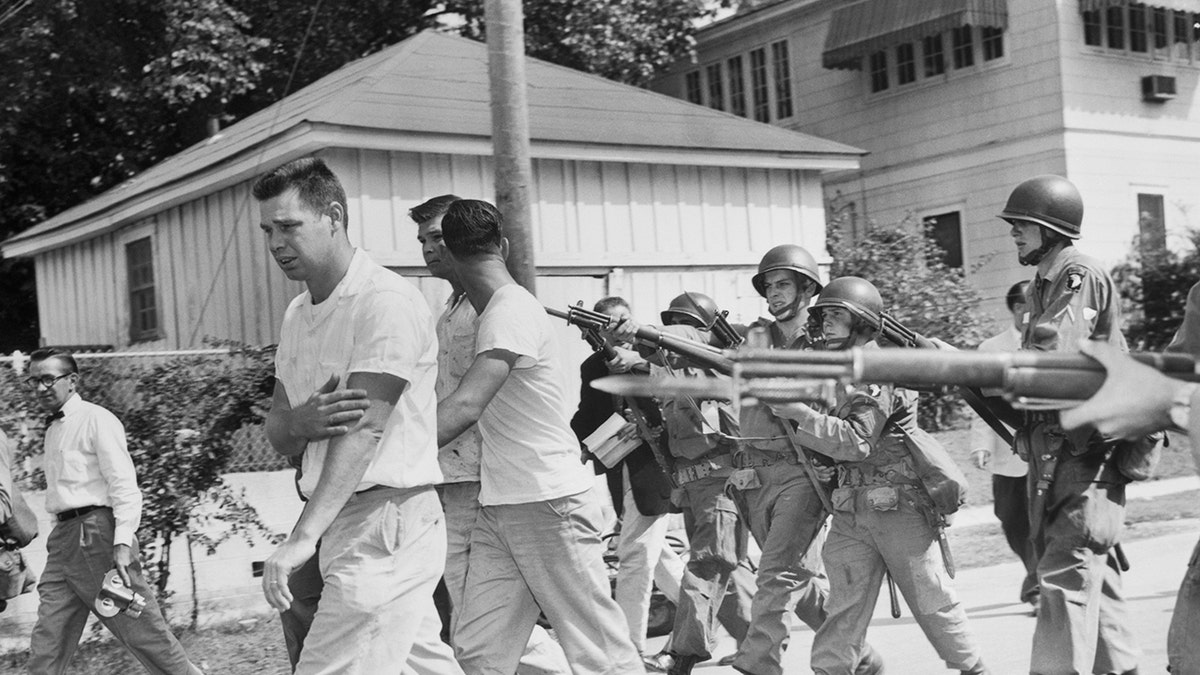 Three men from the mob around Little Rock's Central High School are driven from the area at bayonet-point by these soldiers of the 101st Airborne Division September 25th. The presence of the troops permitted the nine black students to enter the school with only minor background incidents.