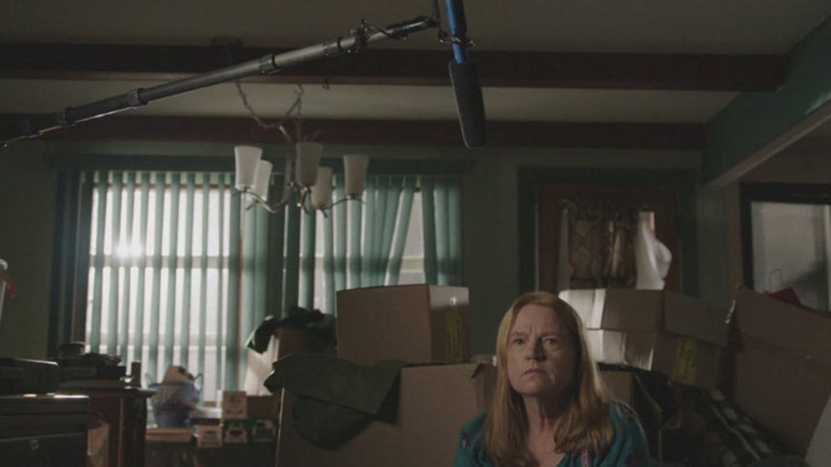 Asa Ellerup wearing a blue blouse and sitting in front of a mic over her head.