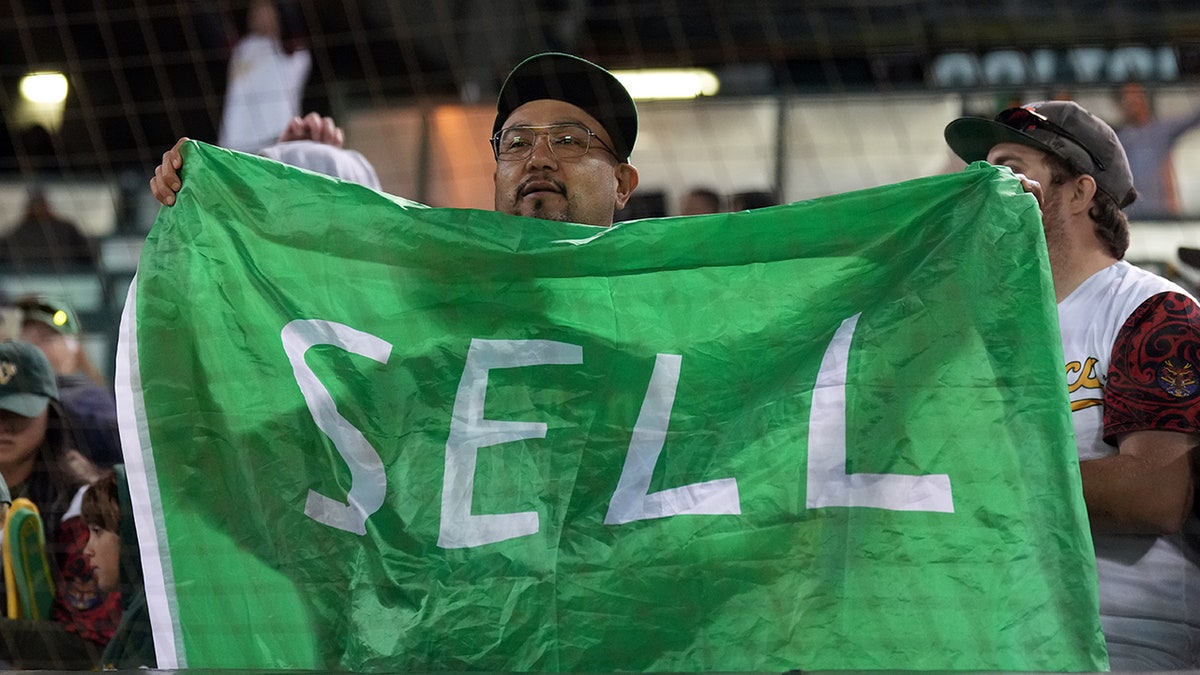 Athletics fan holds up flag reading 'SELL'