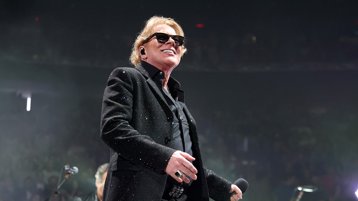 Axl Rose wearing each achromatic pinch sunglasses connected a shape smiling.
