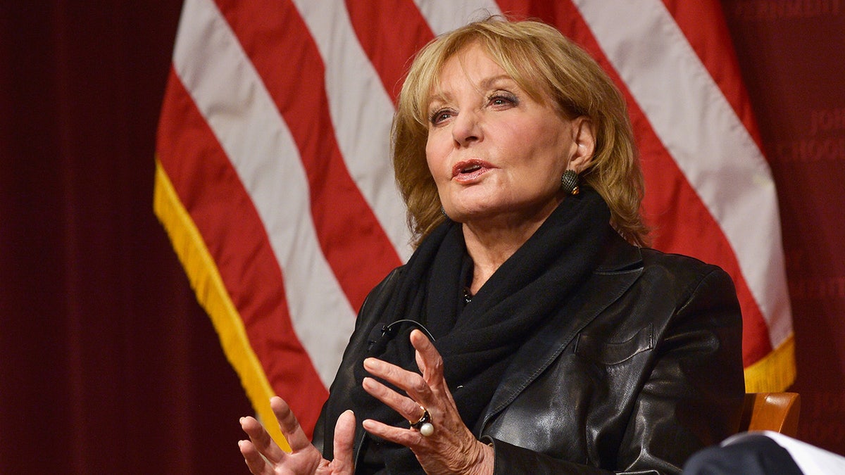 Barbara Walters speaking in front of American flag