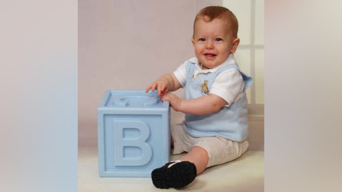 Bryce Balfour wearing airy  bluish  overalls and playing with a ample  block
