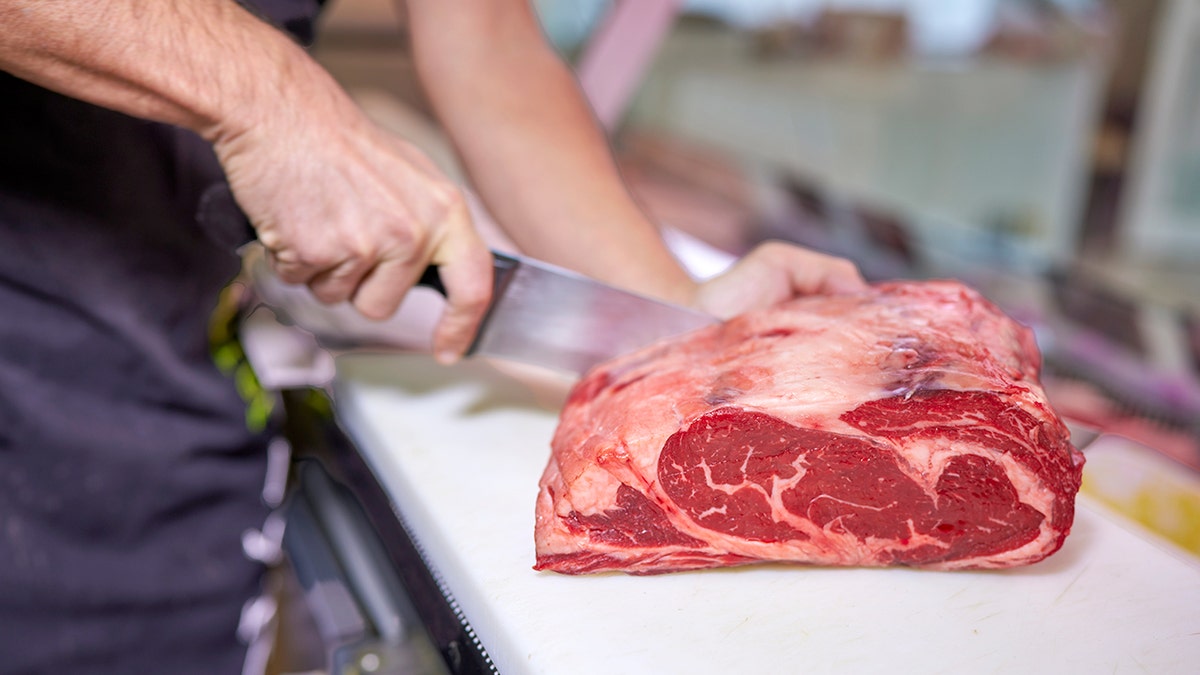 A butcher cut a piece of meat with a knife.