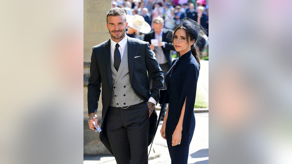 David Beckham and Victoria Beckham in formal wear outdoors for Prince Harry and Meghan Markle's wedding.