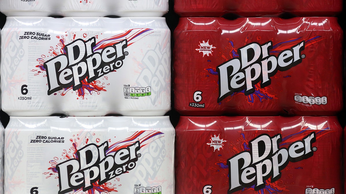Six-pack cases of Dr. Pepper Zero Sugar and Dr. Pepper cans are shown on a shelf.