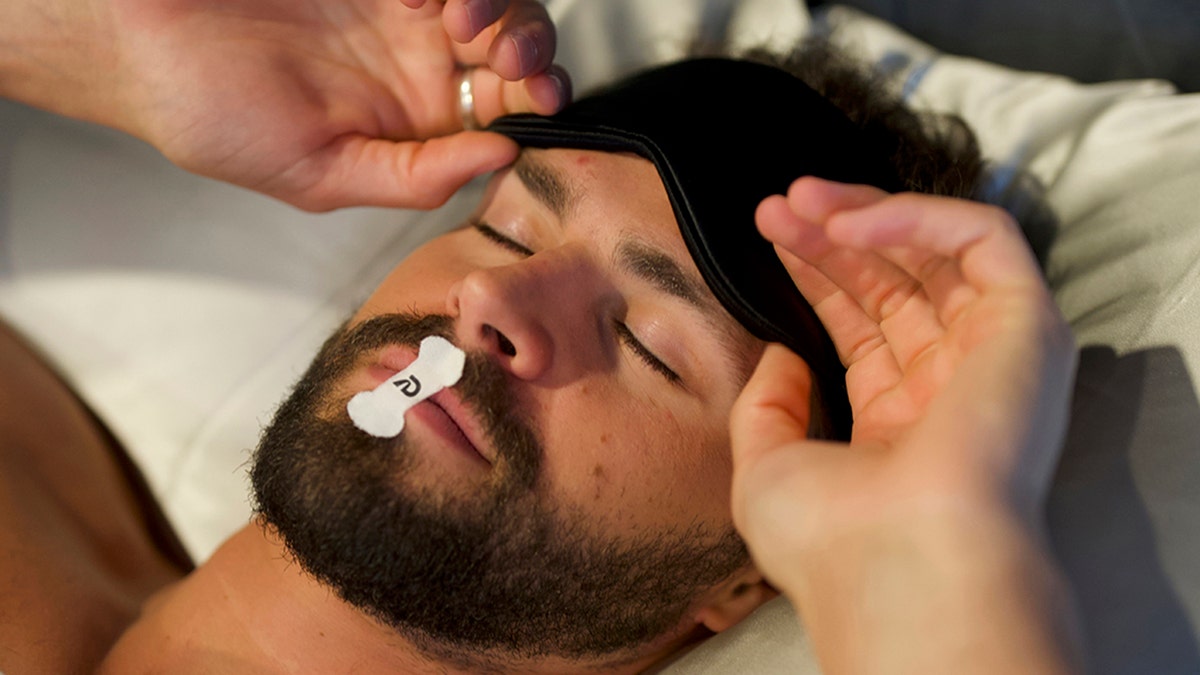man prepares to sleep with mouth tape on