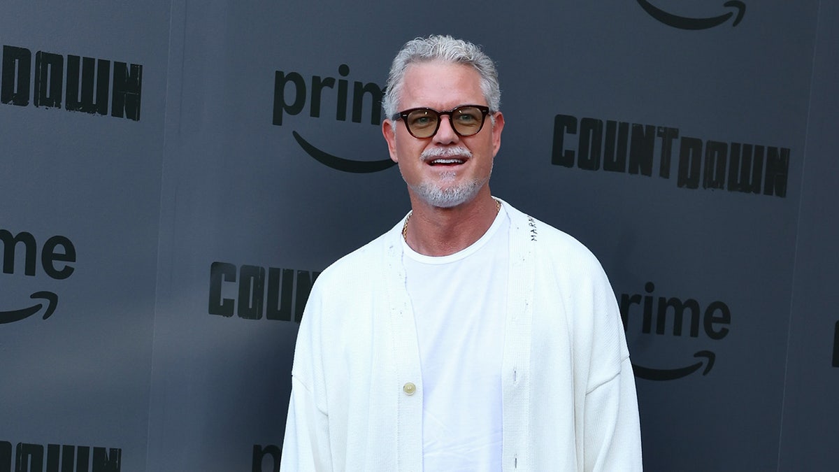 Eric Dane smiles while wearing a white shirt and glasses