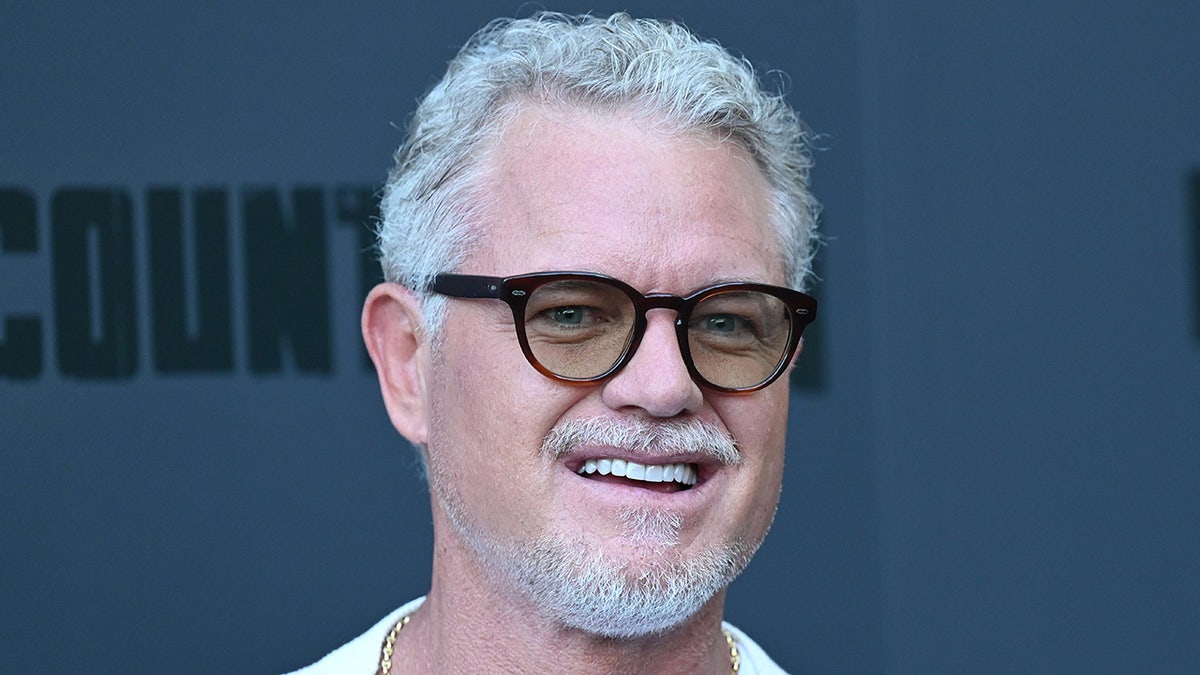 Eric Dane smiles while wearing dark glasses.