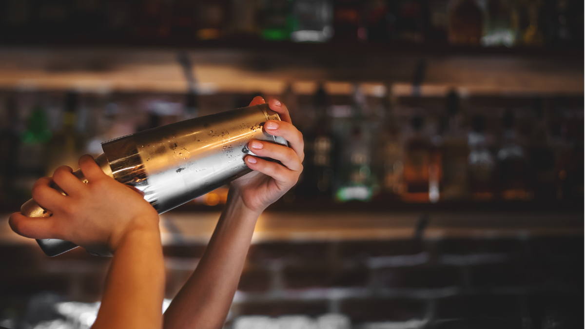 Bartender shaking martini in dark bar