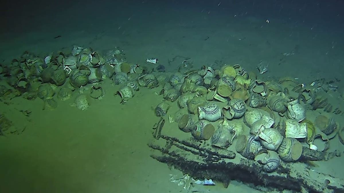 Wide shot of debris, cargo near abandoned shipwreck