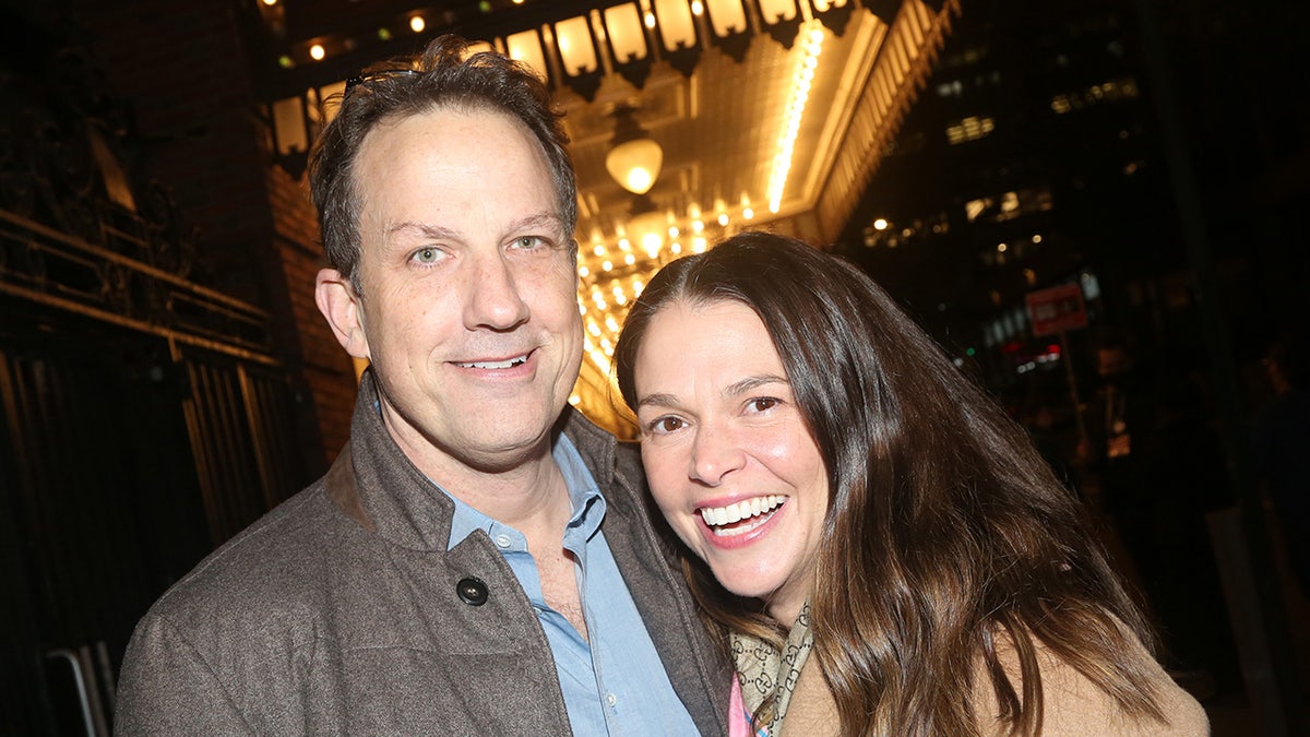 Ted Griffin and Sutton Foster smiling together in front of a marquee