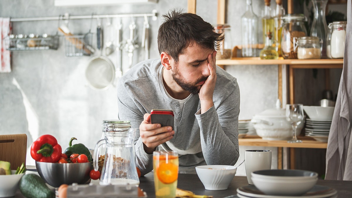 sad man with phone having breakfast