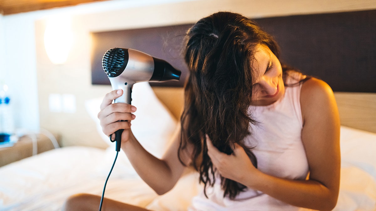 The woman dries her with a blowman