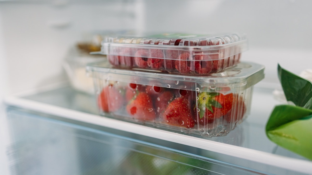 Plastic container of strawberries, raspberries in the refrigerator
