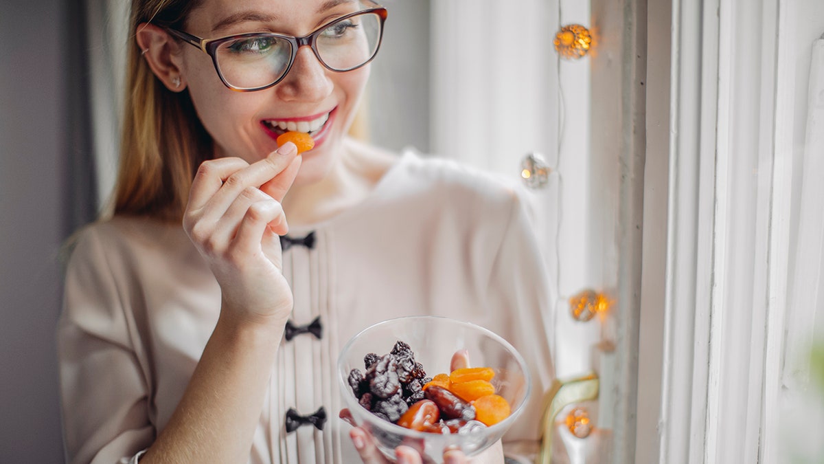 woman eating dried fruit from a bowl