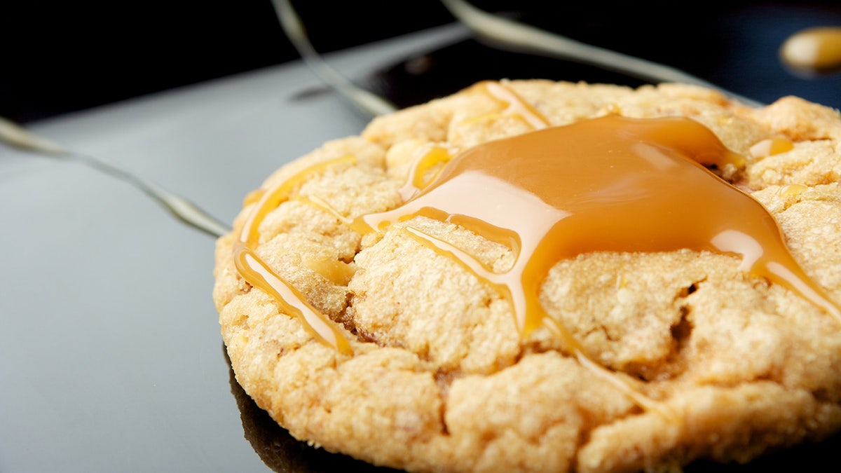 One peanut butter cookie with caramel drizzled on top. Close up shot. Selective focus.