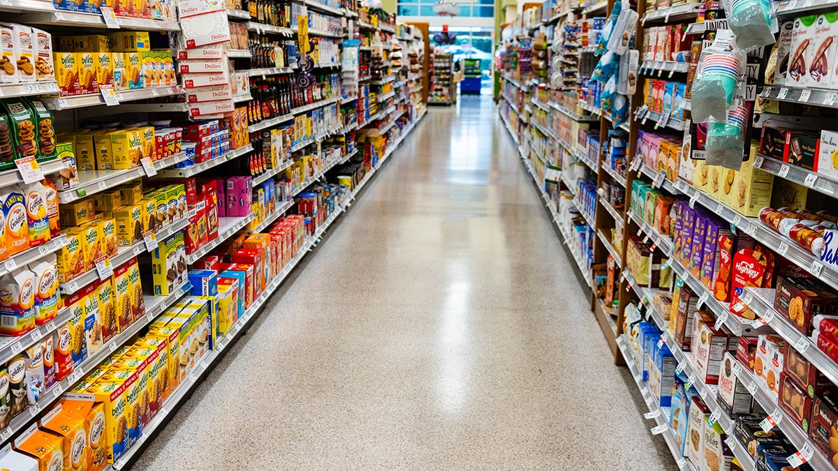This aisle in a supermarket is fully stocked with non perishable food and dry goods.