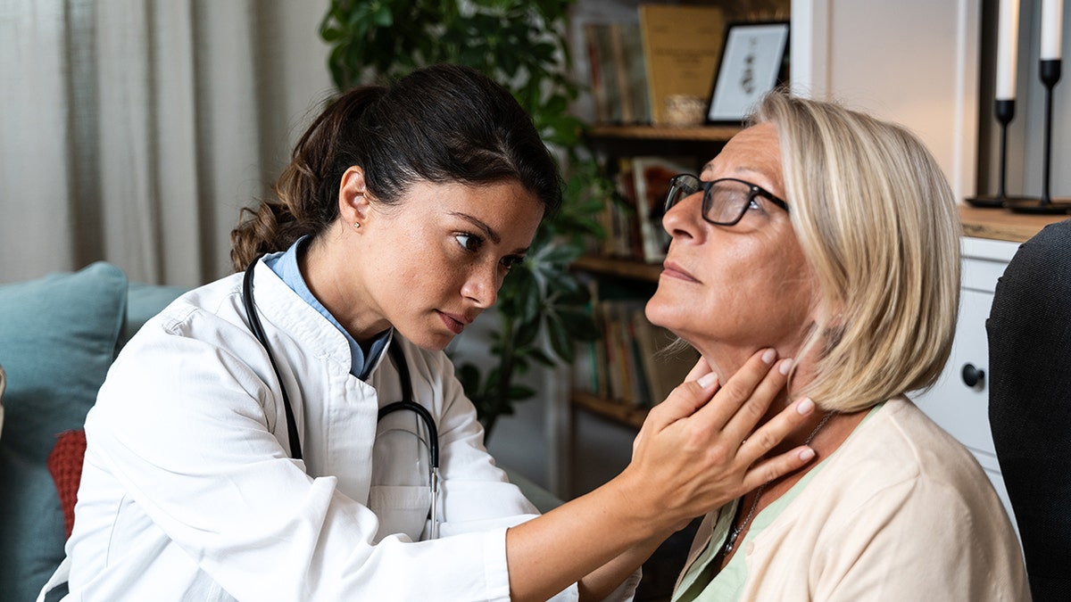 The doctor feels the patient's throat.