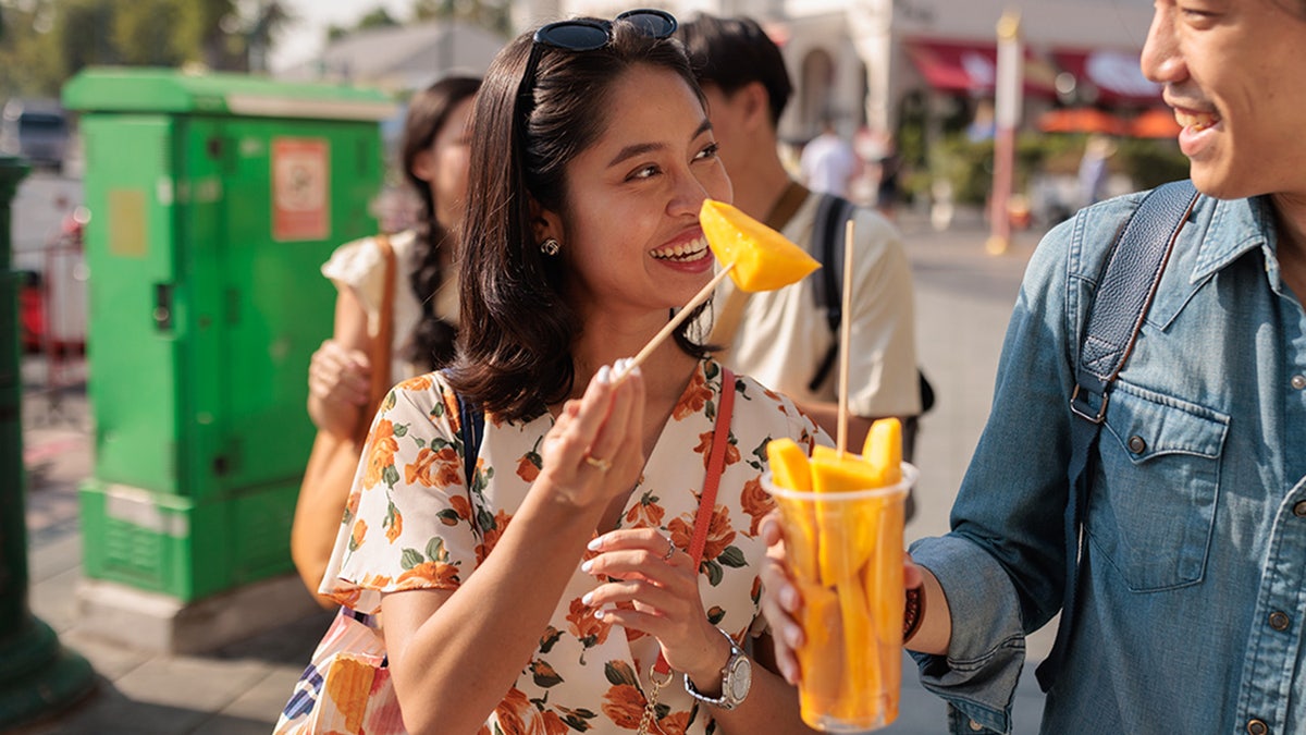 couple eats mango while walking