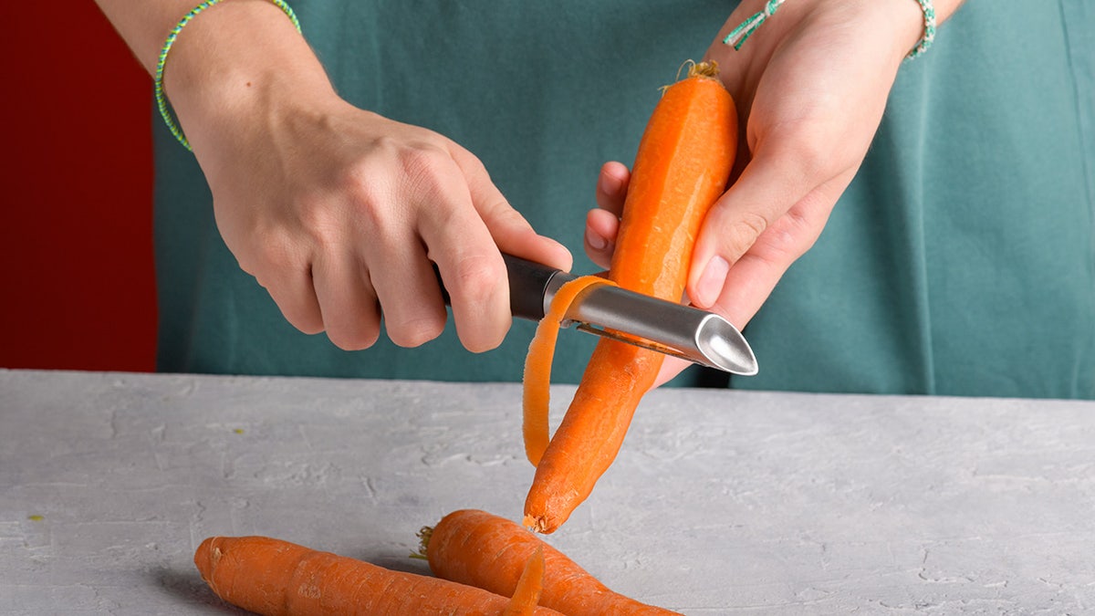 Hands peeling a ample carrot