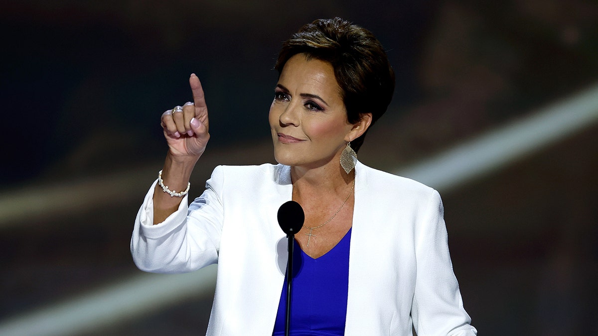 Kari Lake pointing and speaking at a podium