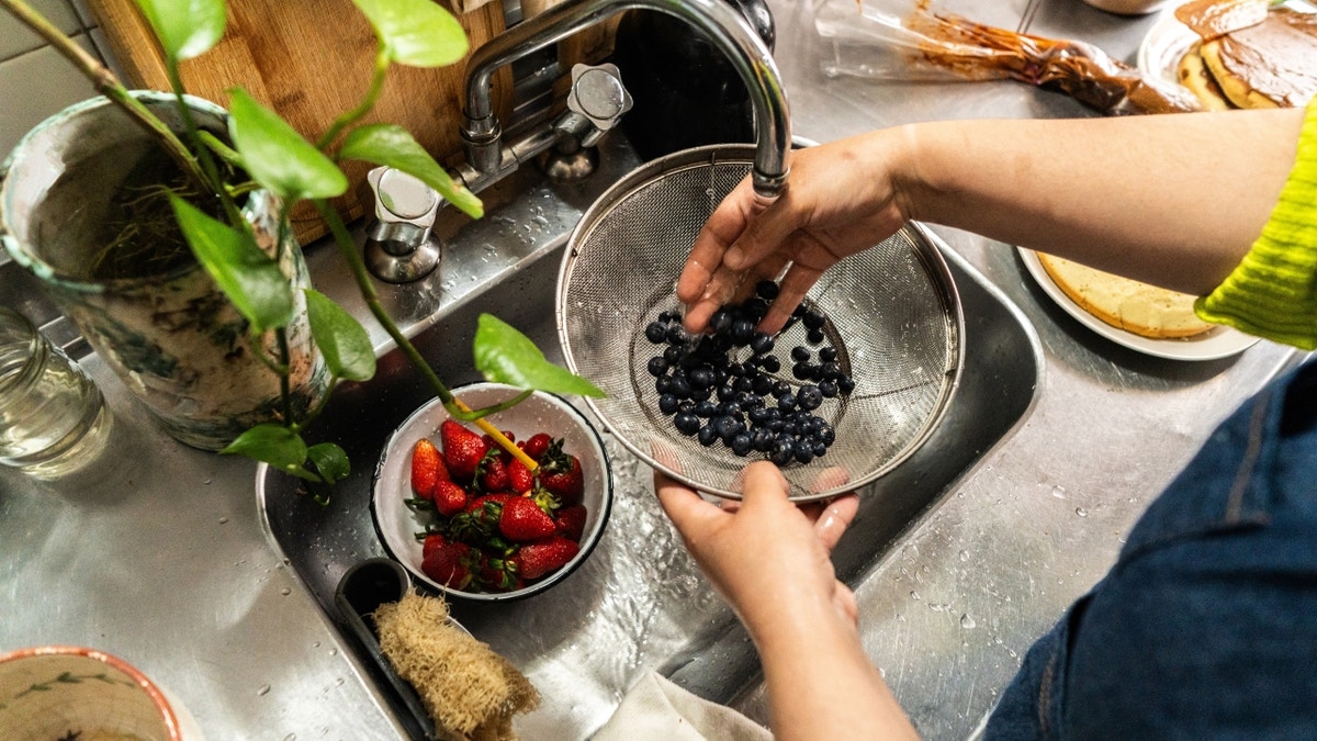 Person washing berries in the sink
