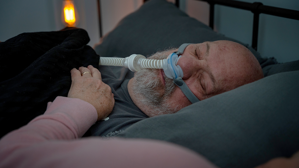 man with sleep apnea sleeps with c-pap