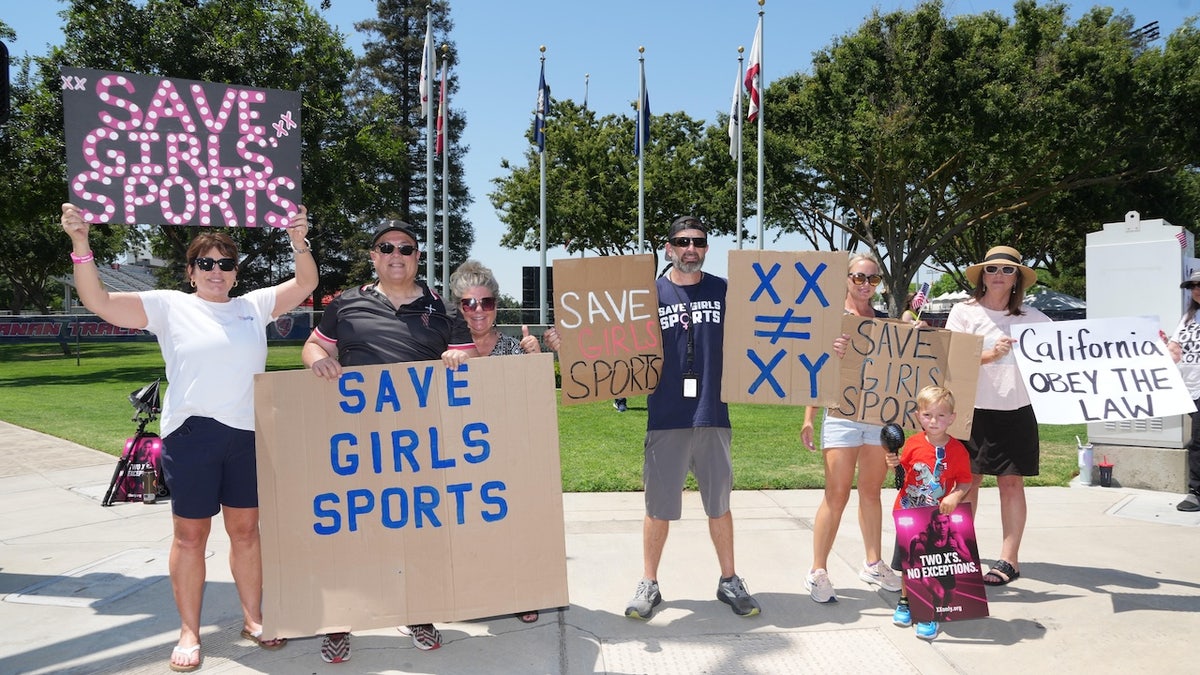 People hold Save Girls Sports signs in protest of transgender athlete AB Hernandez of Jurupa Valley (not pictured) during the CIF State Track and Field Championships at Veterans Memorial Stadium on May 30, 2025 in Clovis, California.