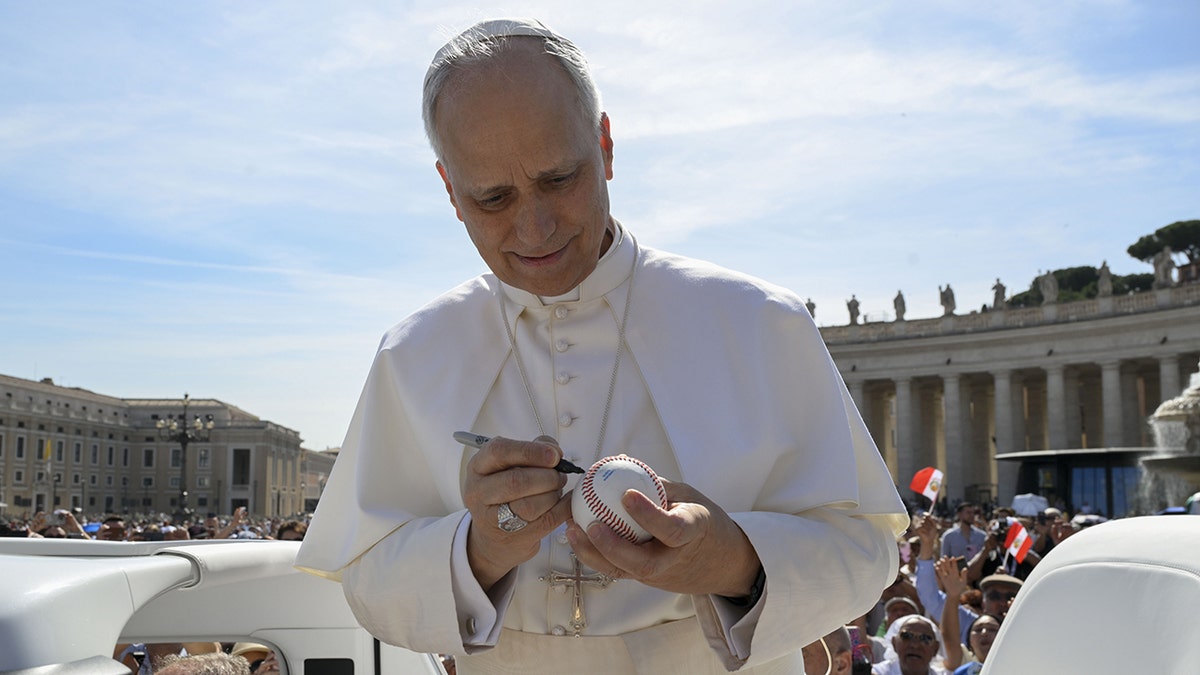 Pope Leo XIV signs a baseball