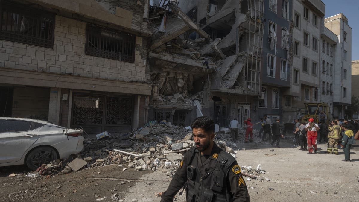 An Iranian policeman walks past a residential building that is destroyed in Israeli attacks in Tehran, Iran, on June 13, 2025.