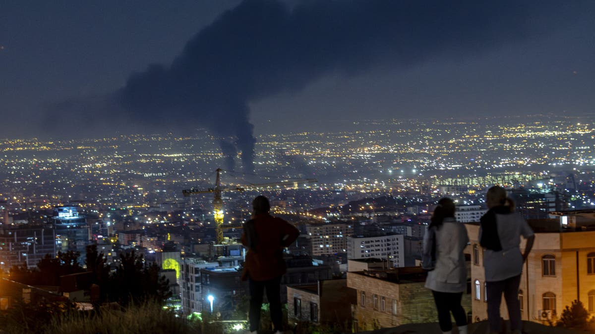 People gather on a hill to watch smoke rising in the distance from an Israeli airstrike in Tehran, Iran, on June 14, 2025. Iran's foreign minister said the country would respond "decisively and proportionally" to a wave of attacks that Israel launched beginning in the early hours of June 13. The attacks targeted multiple military, scientific and residential locations, as well as senior government officials.
