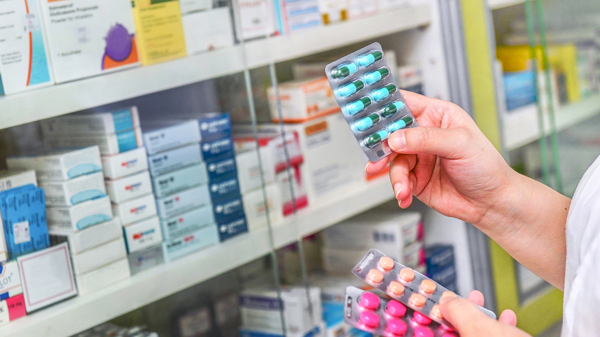 Hand holding medicine capsule pack at the pharmacy drugstore.