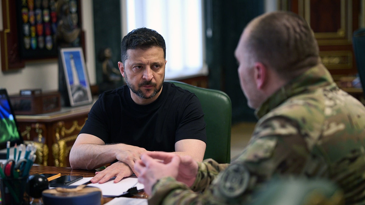 Ukrainian President Volodymyr Zelenskyy listens during a meeting with a senior military officer
