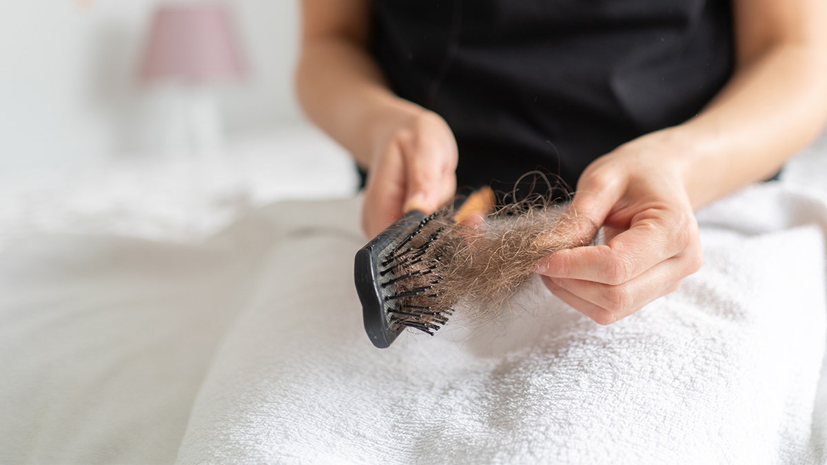 woman pulls hair out of brush