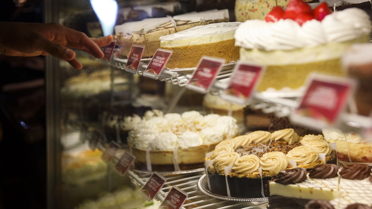 A hand points to a cheesecake on display at a Cheesecake Factory restaurant in 2017.