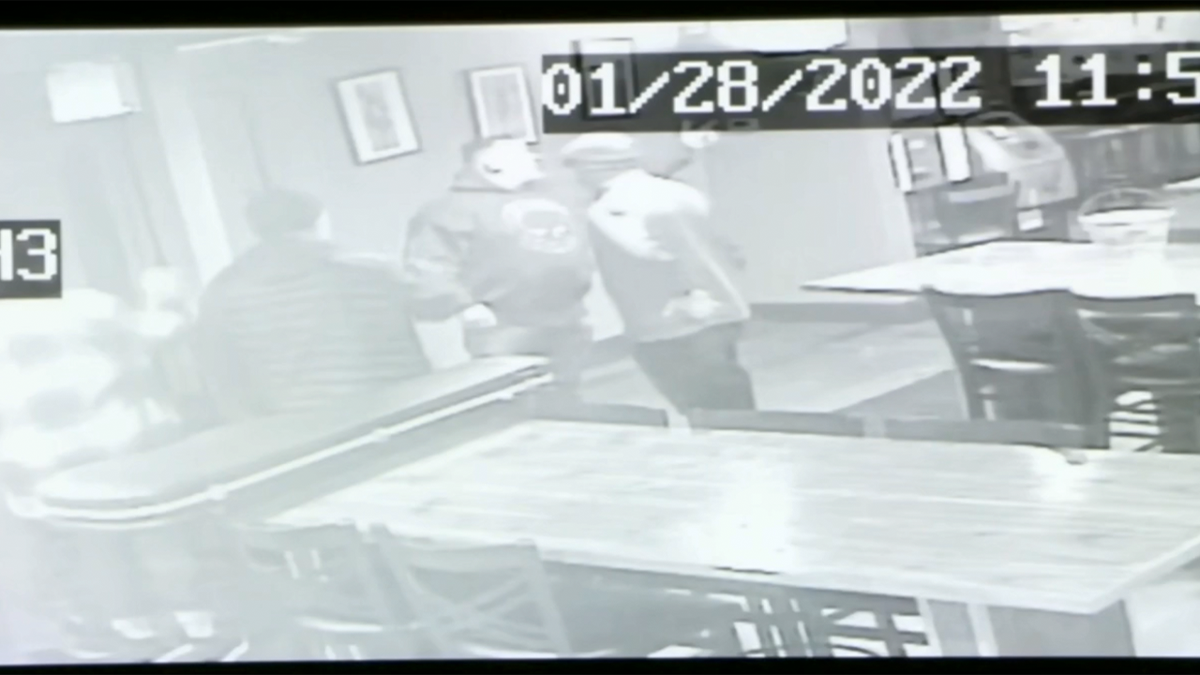 higgins gestures off-camera in a black-and-white still from surveillance video