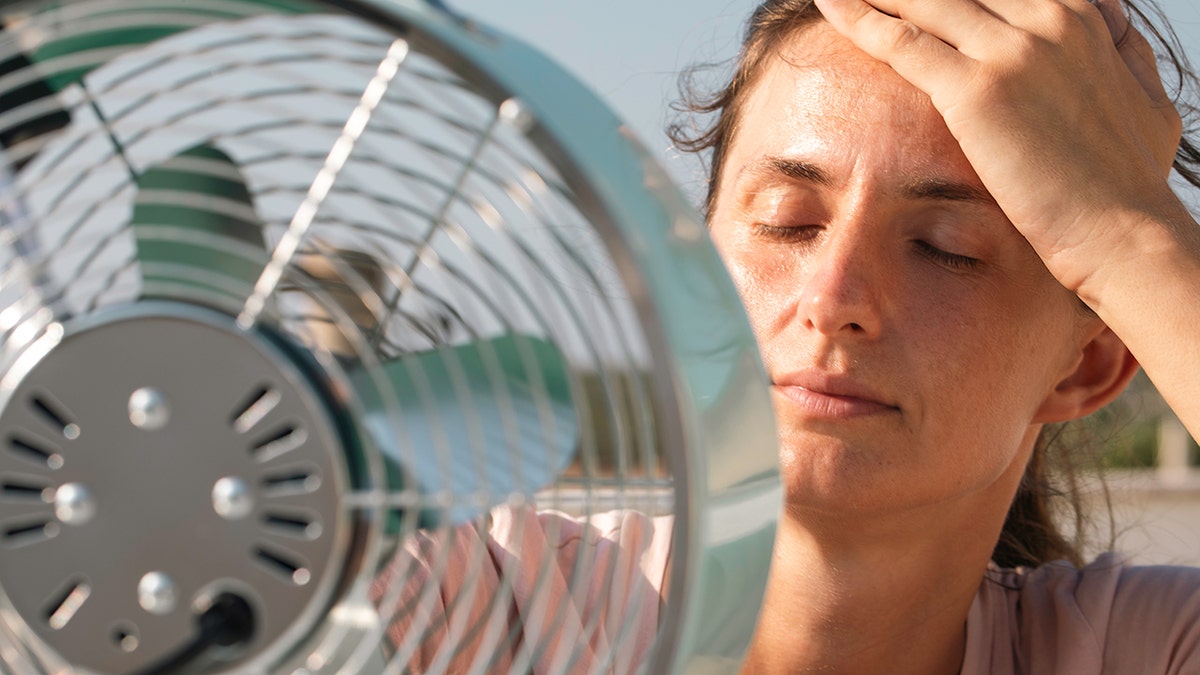 woman cools down in front of fan