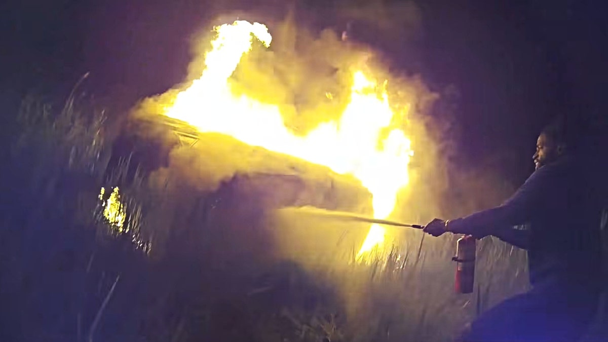 Screenshot of crash footage shown by a good Samaritan extinguishing flames with a fire extinguisher