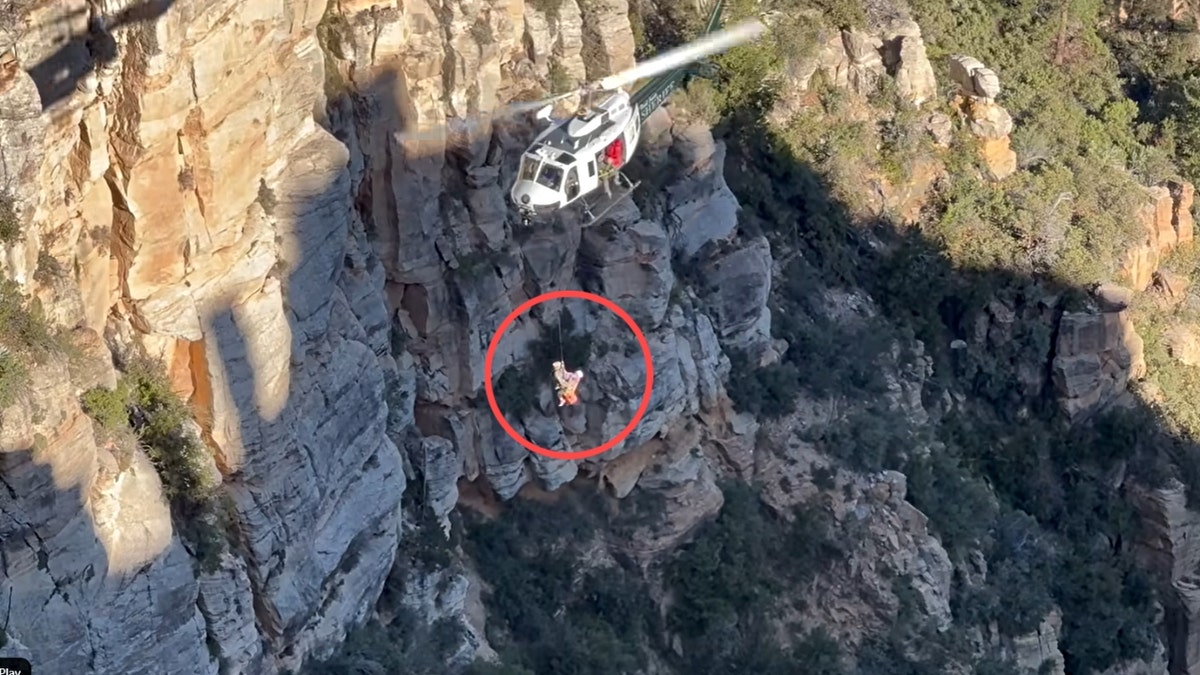 Rescue officials carry Janelle Banda into a helicopter using a harness