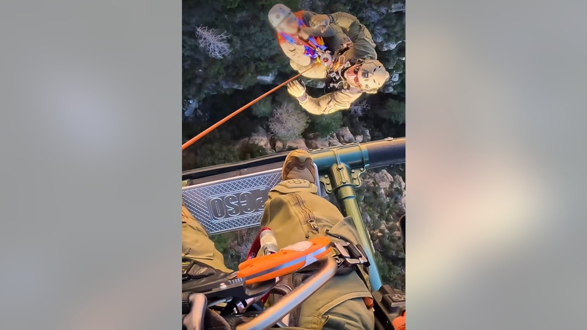 Rescue officials carry Janelle Banda into a helicopter using a harness