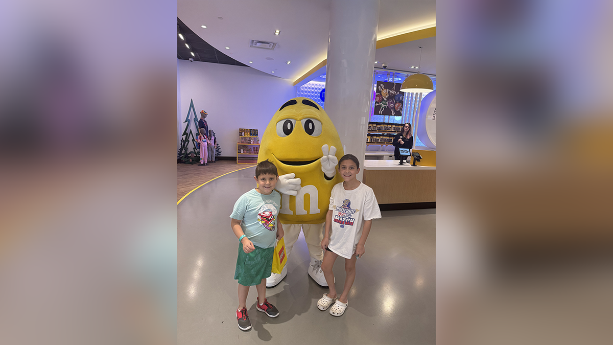Preston Patton with his sister next to a giant yellow M&M mascot