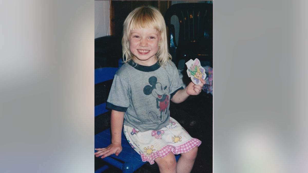A young Emily Ferlazzo smiling wearing a Mickey Mouse shirt.