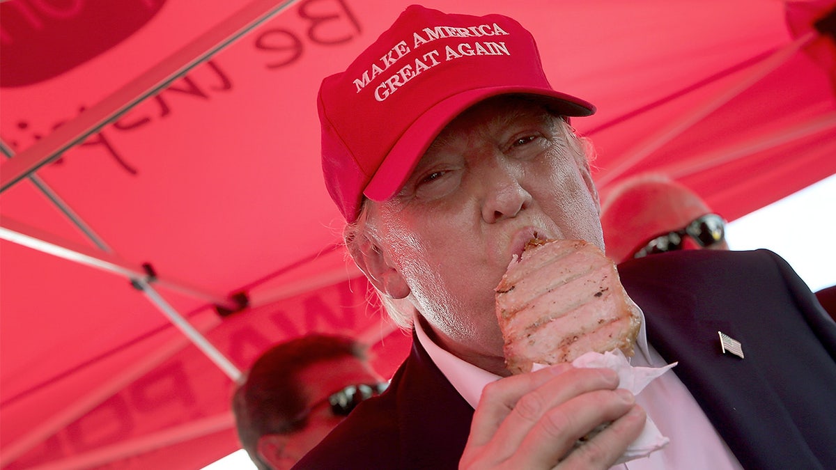Trump eating pork cutlet on stick with MAGA hat