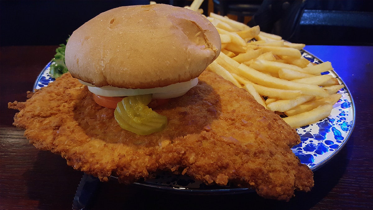 Pork tenderloin sandwich on plate with fries
